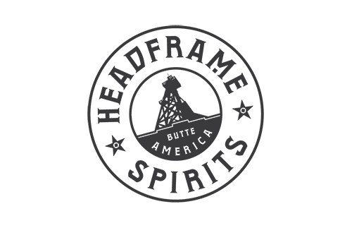 Logo featuring a circular design with the text "HEADFRAME SPIRITS" around the outer edge. Inside, an illustration of a mining headframe with the words "BUTTE AMERICA" below it. Two star icons on each side of "SPIRITS.