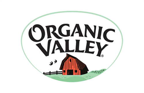 Logo of Organic Valley with stylized text above a red barn, black birds, and a green landscape. The design is enclosed in an oval shape with a light green border.